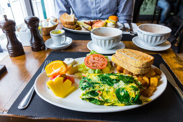 Brunch close up. Beautiful delicious plate with french spinach omelette, toasts, fried potatoes, salad, fruits. Served with hot chocolate.  