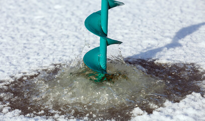 Ice augers for fishing. Winter frosty fishing on the river. Winter fishing