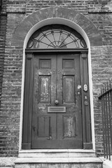 Beautiful ancient front entrance door of a beautiful typical house in the english capital, London. Monochrome photography (retro style,  black and white). Vertical shot.