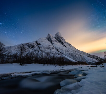Mountains and starry night sky in motion, Senja islands, Norway. Winter landscape with night sky. River and mountains at the winter time. Norway travel image
