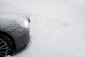 the car is in the snow, the headlight is shining in the dark winter time on the street. copy space