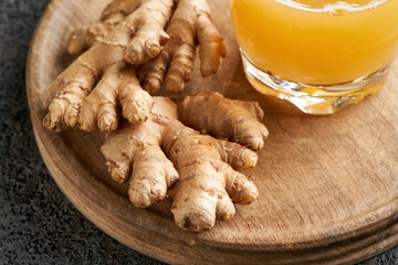 Fresh ginger root on a wooden cutting board, with natural probiotic drink containing ginger