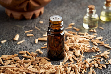 A dark bottle of essential oil with cedar wood chips