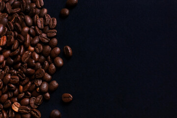 Fresh roasted coffee beans closeup on black stone background. Top view, flat lay with copy space