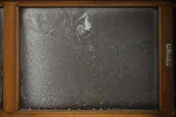Frost patterns on the window in a wooden frame. Cold winter.