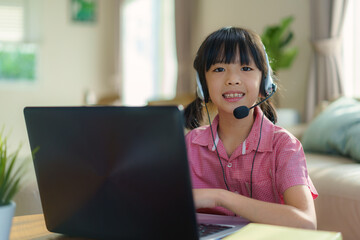 Asian girl student video conference e-learning with teacher and classmates on computer in living room at home. Homeschooling and distance learning ,online ,education and internet.