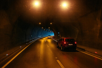 Road tunnel in mountain illuminated by lamps
