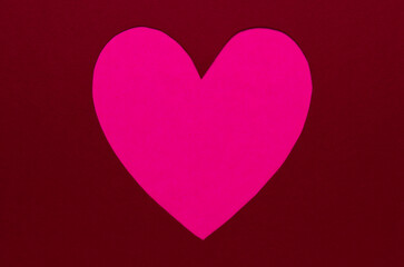 A pink heart on a red paper background