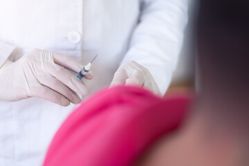 Young Female doctor in protective mask injecting or prepairing for injecting vaccine against coronavirus or ncov 19 or covid into patient's arm