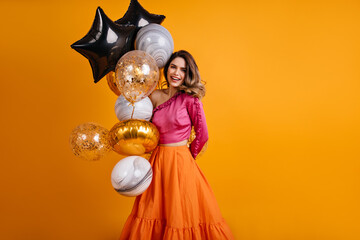 Enthusiastic girl posing with balloons in her birthday. Photo of gorgeous woman celebrating holidays.