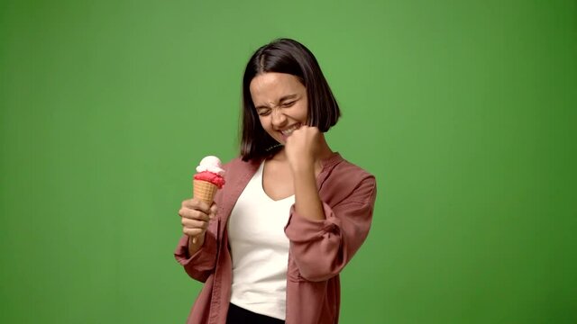 Young woman holding a cornet ice cream celebrating a victory and surprised to be successful