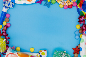 Frame of various sweets and utensils for children's birthdays or parties with blue background and copy space