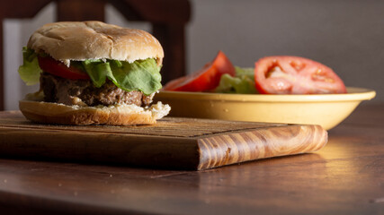 homemade burger on a wooden board. with lettuce and tomato. fast food.