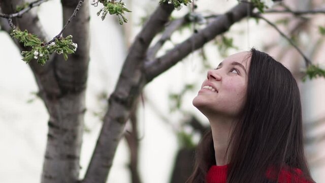 Young smiling girl enjoys tree blossom flowers, positive energy and emotion concept