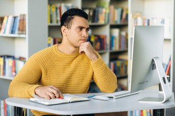 Hispanic man freelancer search ideas in the internet, using computer. Concentrated employee working...