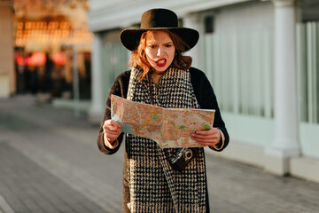 Angry female traveler looking at city map. Sad woman in hat and coat trying to find right direction.