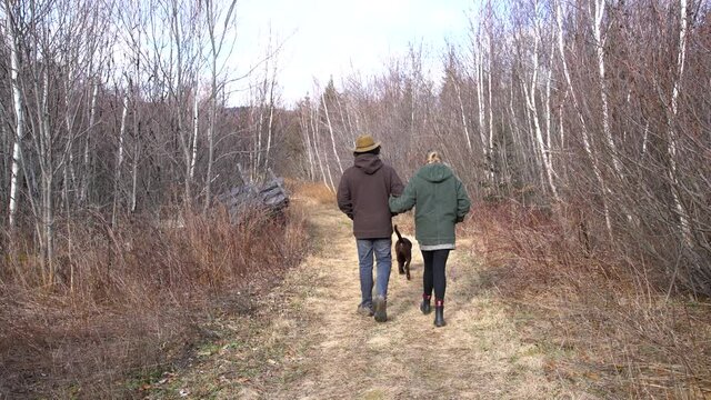 A mother and son walking on a woodland trail in the winter