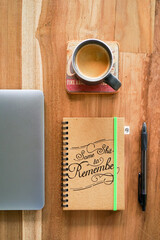 Notebook, laptop, pen and cup of coffee sitting on top of a wooden table