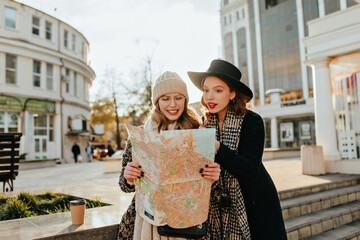 Lovely girl looking at map during city travel. Outdoor shot of european ladies exploring town.