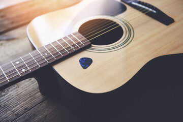 Guitar resting on old wooden background, Close up acoustic guitar and Guitar pick.