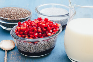 Chia seed pudding with raspberry jam and pomegranate seeds. Ingredients close up on wooden background