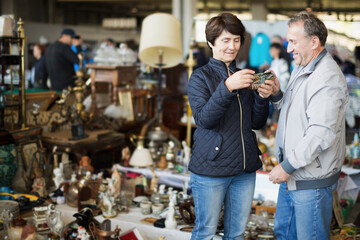 Loving mature family couple choosing vintage things at sale on market