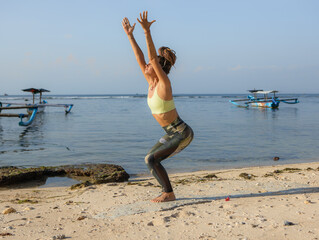 Caucasian woman practicing Utkatasana, Chair Pose. Low squatting asana in hatha yoga. Hands raised...