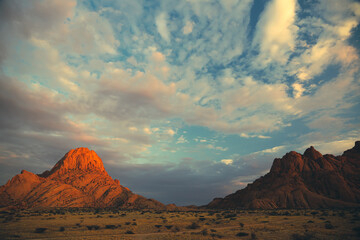 Fototapeta premium Illuminated mountain peaks at dusk in Spitzkoppe, Namibia