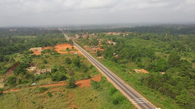 Aerial jungle highway tree landscape truck traffic Gh. Roads, streets are poorly maintained rough dirt. Cultural capital of historical Ashanti Empire. Third world poor poverty areas with small shacks.