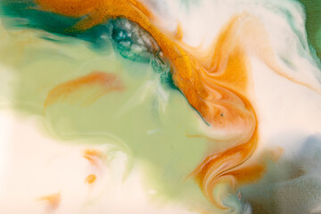 Bright flowing alcohol Ink gold colors on blue green background. Acrylic Fluid Art. Liquid marble texture for abstract artwork. Transparent creativity.