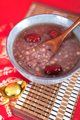 A bowl of eight treasures porridge and wooden spoon on a red background