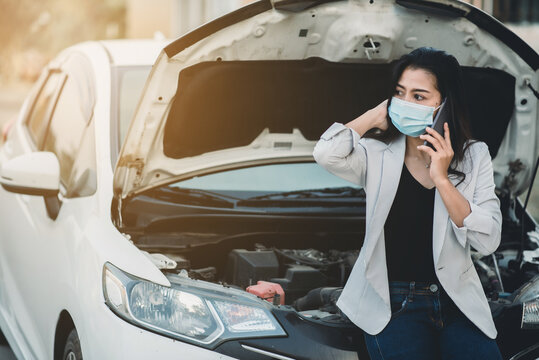 Asian girl She was wearing a Covid-19 virus mask and she was using her smartphone to call out car insurance.