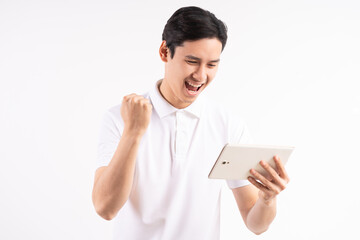 Image of happy young man standing on isolated white wall background. Look aside using the tablet as...