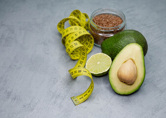 Cleansing of the body. Vegan concept. Food for weight loss. Proper nutrition. Raw avocado with measuring tape on grey background. Healthy balanced diet concept, weight loss, calorie counting.
