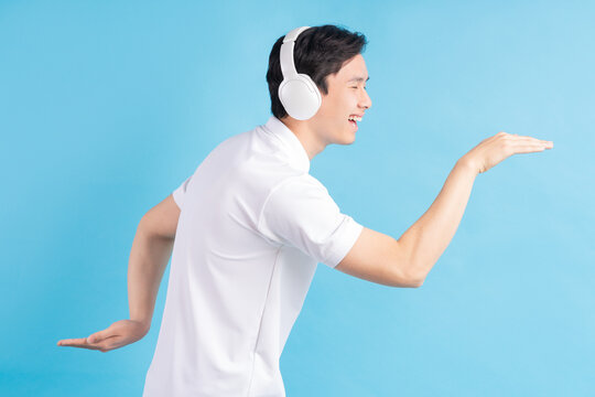 a photo of a handsome Asian man listening to music and dancing to it