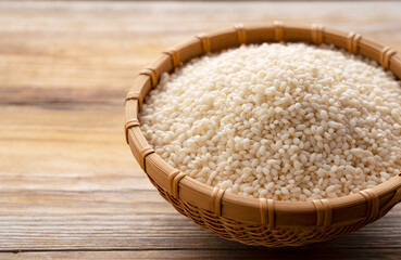 Glutinous rice in a bamboo colander set against a wooden background