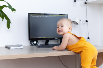 Caucasian funny little baby boy exploring computer, monitor and keyboard