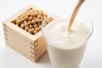 Pour soy milk into a glass placed on a white background