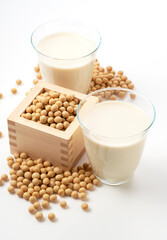 Soy milk and soybeans in a glass on a white background