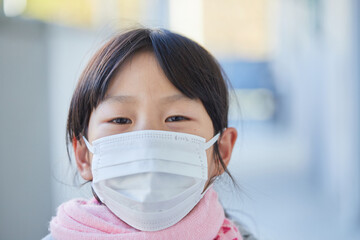 家の廊下にマスクをつけている可愛い子供の顔