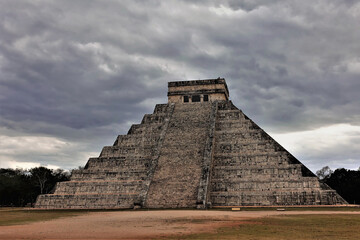 Fototapeta na wymiar The famous pyramid of Kukulkan against the backdrop of a cloudy sky. A staircase leads to the top of the ancient stepped building, to the altar. Unesco heritage. Chichen Itza. Mexico