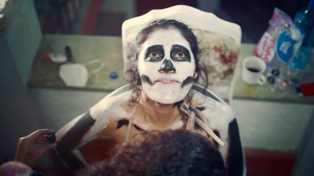 Artist body-painting a woman as a skeleton catrina for the celebration of the day of the dead in Mexico.