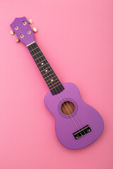 Four string ukulele guitar on pink background