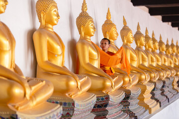 Asian young novice monk are covering cloth Buddha statue in Wat Phutthai Sawan Temple, Ayutthaya, Thailand