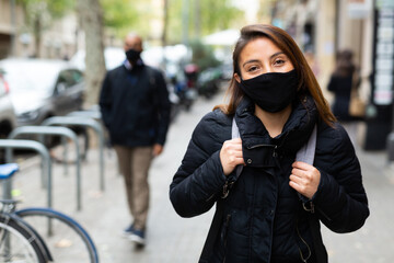 Portrait of young woman wearing face mask for disease protection walking outside at cold day