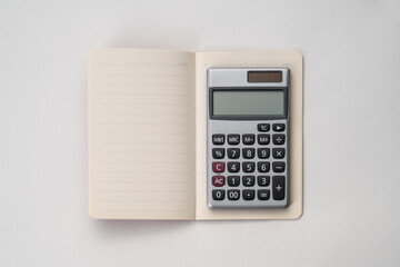 Top view of notebook with a calculator on white isolated background 