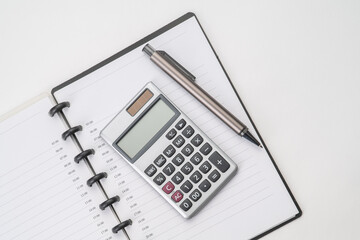 Top view of notebook with pen and calculator with white isolated background 