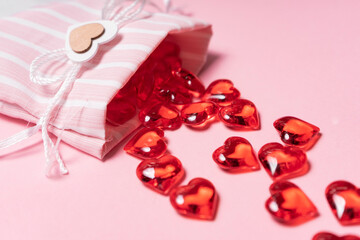 selective focus. Valentine's day card. glass red hearts scattered from a beautiful cloth bag. the view from the top. pink background