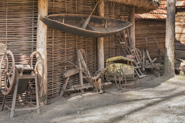 A fragment of a peasant hut under a thatched roof, a boat, equipment and tools for agricultural...
