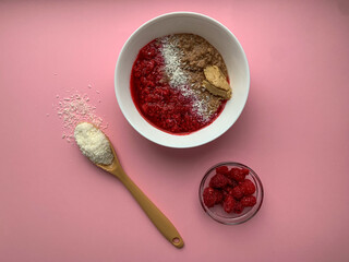 Healthy breakfast. Chocolate porridge with raspberries, coconut chips in a white cup on a pink background. Proper nutrition, vegetarianism, healthy food